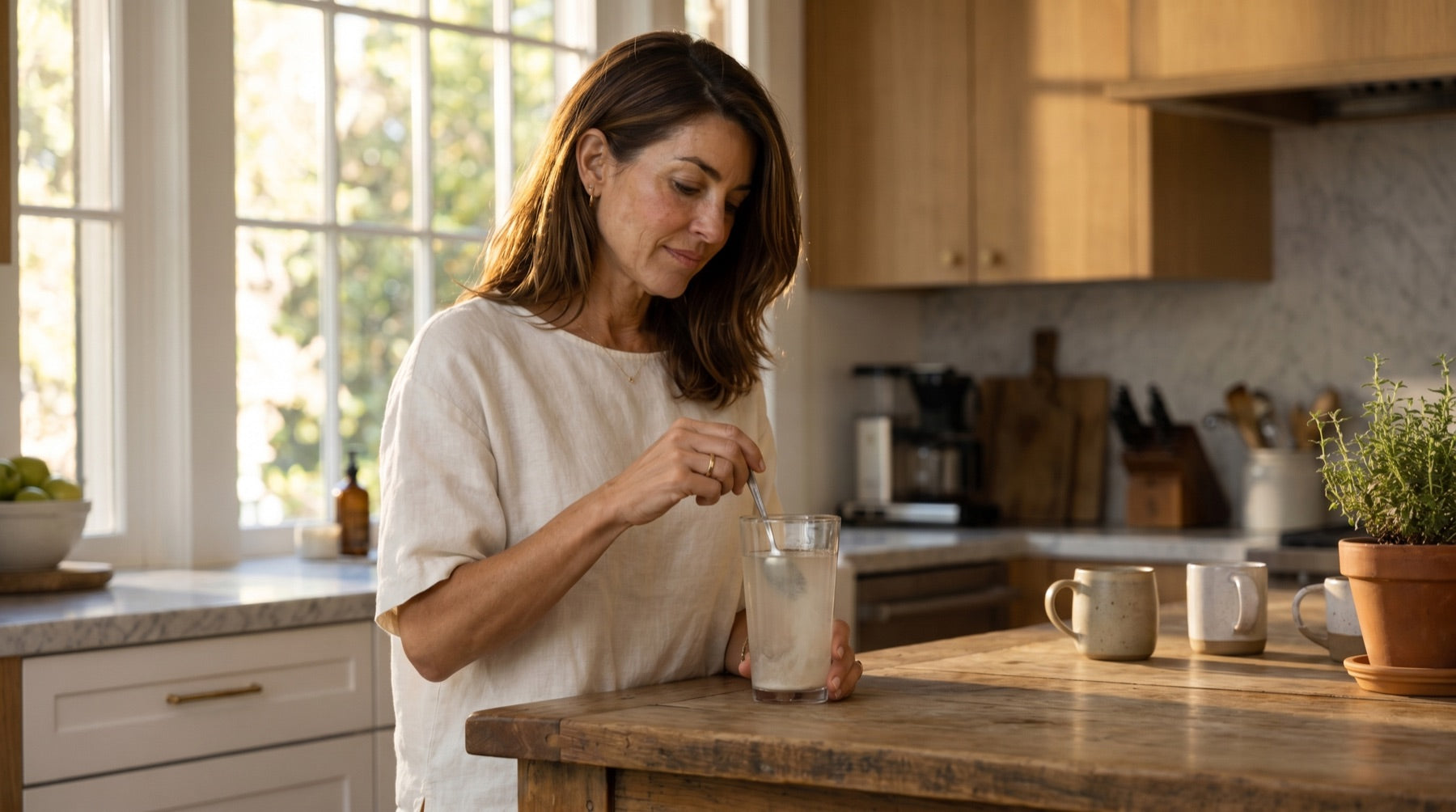 The same woman stirring a scoop of powder into a glass of water, the water turning faintly cloudy.